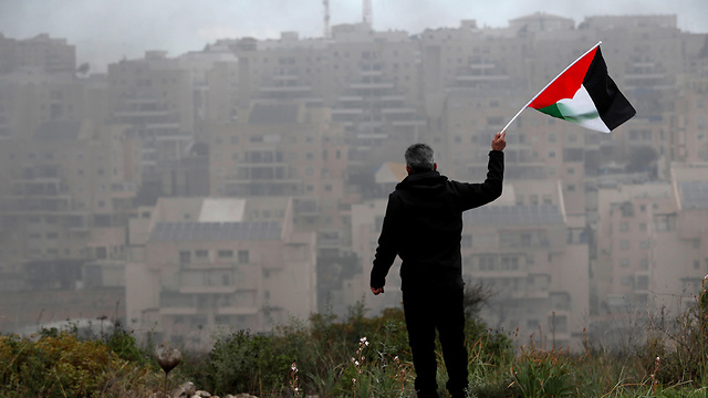 פלסטיני מנופף ב דגל פלסטין מול מודיעין עילית (צילום: רויטרס)