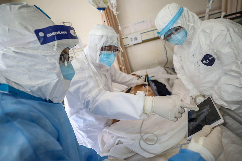 רופא בודק חולה שנדבק בנגיף הקורונה בבית חולים בווהאן (צילום: AFP)