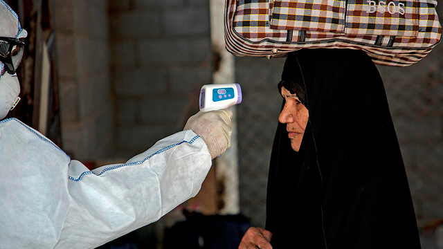 בדיקת חום בכניסה ל עיראק לאנשים שחוזרים מ איראן נגיף קורונה (צילום: AFP)