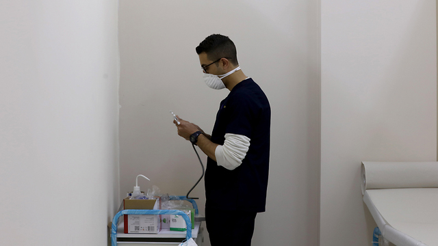 איש צוות רפואי במרכז הרפואי בשכם המטפל בחולי קורונה (צילום:  EPA)