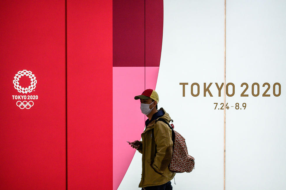 אזרח יפני ליד כרזת המשחקים (צילום: AFP)