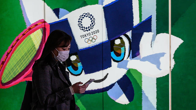 אזרחית יפנית ליד תמונת הקמע של המשחקים (צילום: AFP)