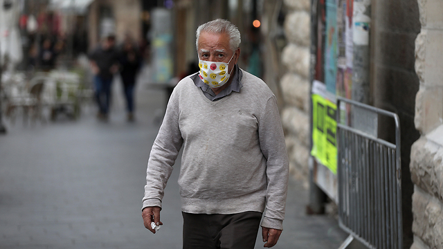 Мужчина в маске на улице Иерусалима. Фото: EPA