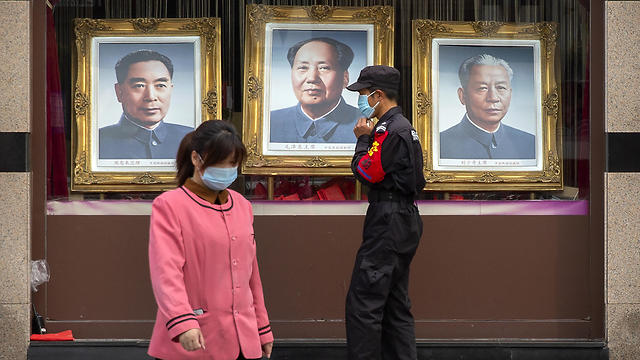 עובד ביטחון סיני מול תמונות של מנהיגי האומה (צילום: AP)