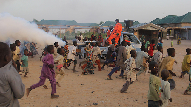 מיידוגורי ניגריה ילדים רצים אחרי רכב שעושה חיטוי  (צילום: AFP)