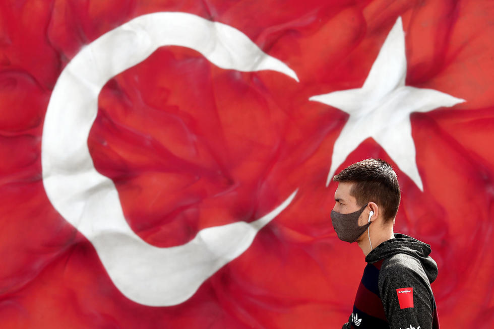 צעיר עם מסכה וברקע דגל טורקיה איסטנבול טורקיה קורונה (צילום: EPA)