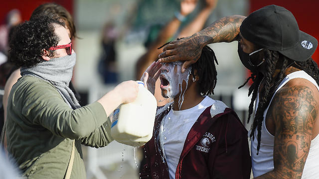 שופכים חלב על מפגין שנפגע מגז מדמיע במיניאפוליס, מותו של ג'ורג' פלויד (צילום: EPA)
