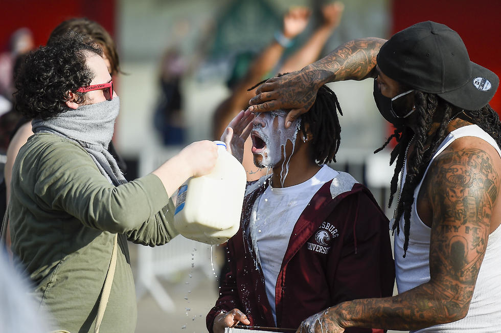 Демонстранты промывают молоком глаза человеку, пострадавшему от слезоточивого газа. Фото: EPA (צילום: EPA)