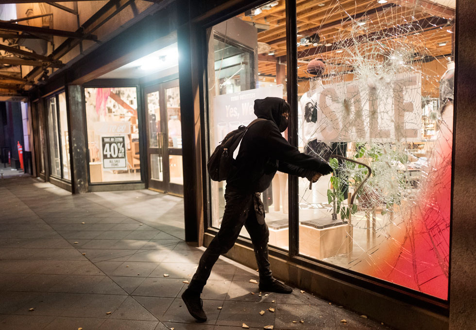 מפגין שובר חלון ראווה במהלך ההפגנות בסוף השבוע (צילום: AP)