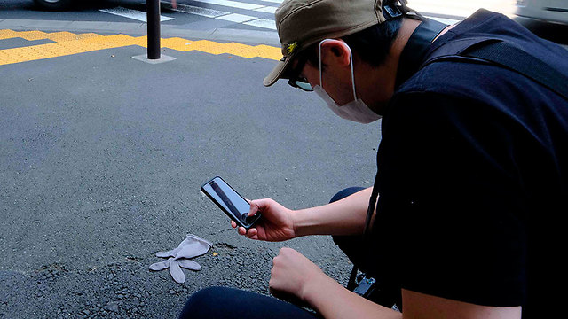 יפן קוג'י אישי מצלם כפפות נטושות ב רחוב נגיף קורונה (צילום: AFP)