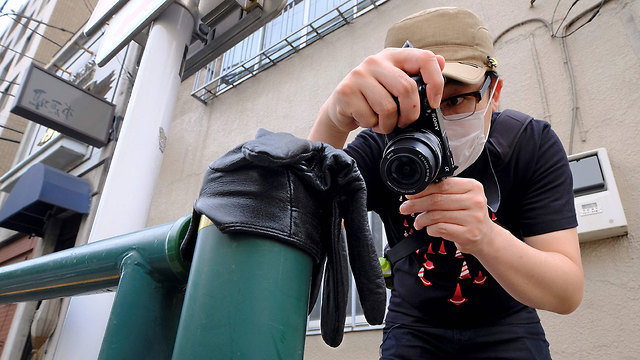יפן קוג'י אישי מצלם כפפות נטושות ב רחוב נגיף קורונה (צילום: AFP)