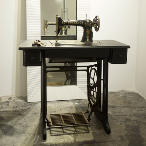 באחד מתאי המדידה עומדת מכונת תפירה עתיקה, שעוברת במשפחתו כפריט נוי (צילום: רותם לבל)