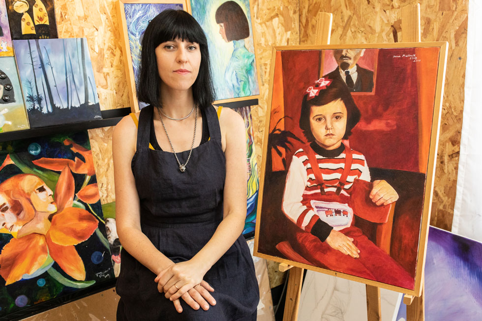 יאנה סטופ לצד דיוקן עצמי שלה כילדה. "כישרון הציור הציל אותי. כשהייתי מציירת, הייתי מרגישה בטוחה ומוגנת" (צילום: אילנית תורג'מן)