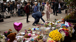 מנחמים מניחים פרחים ונרות לזכר הנרצחים במנצ'סטר, לפני שבע שנים