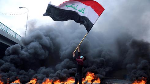 An Iraqi protester waves the national flag  (Photo: Reuters)