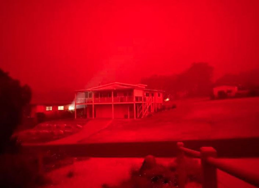 A red haze hangs over Mallacoota as devastating wildfires sweep the state of Victoria ()