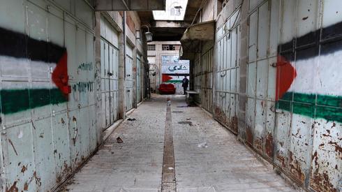 A Hebron street in Hebron is painted with Palestinian flags (Photo: AFP) יהודה ושומרון העיר חברון
