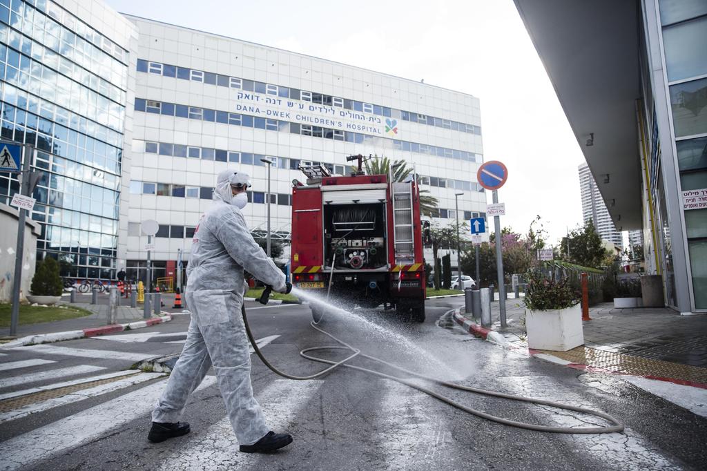 A worker disinfects the entrance to Ichilov Hospital in Tel Aviv  ()