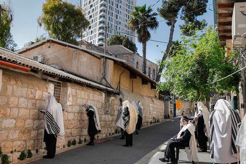 Haredi men practice social distancing as they pray outside a synagogue in Jerusalem  (Photo: AFP)