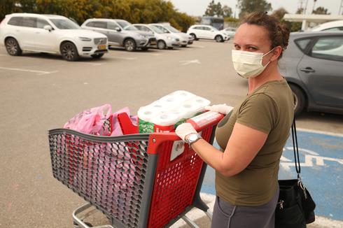 An Israeli woman wears a protective mask while shopping  (Photo: Elad Gershgoren)