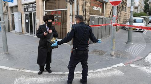 A police officer talks to a resident of the predominantly Haredi city of Bnei Brak during strict closure to halt coronavirus  (Photo: EPA)