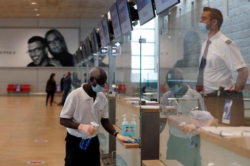 An employee disinfects surfaces at a counter in the departures terminal at Ben Gurion Airport 