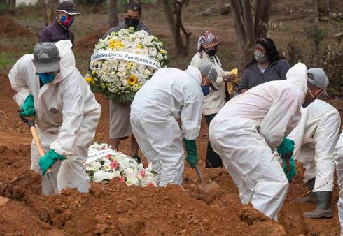 Undertakers in Brazil, wearing protective gear, bury coronavirus victims  (Photo: AP)