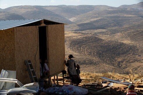 Israeli settlers stand beside a temporary structure in the West Bank outpost of Maoz Ester (Photo: Reuters) A settler and children stand next to a temporary structure in the West Bank outpost of Maoz Ester