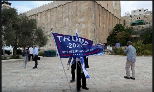 An Israeli settler in Hebron shows support for former U.S. president Donald Trump ahead of the in Nov. 2020 presidential elections (Photo: Reuters) An Israeli settler adjusts a flag during a gathering to show support for U.S. President Donald Trump in the upcoming U.S. election, at the Cave of the Patriarchs, in the Palestinian city of Hebron