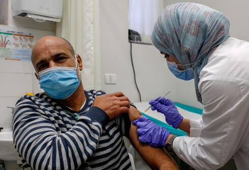 A Palestinian resident of East Jerusalem is inoculated against coronavirus by an Israeli medic (Photo: AFP) חיסונים בירושלים