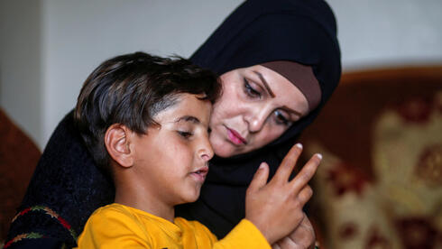     Niveen Gharqoud sits with her son Amir at their home in the middle of the Gaza Strip March 15, 2021 