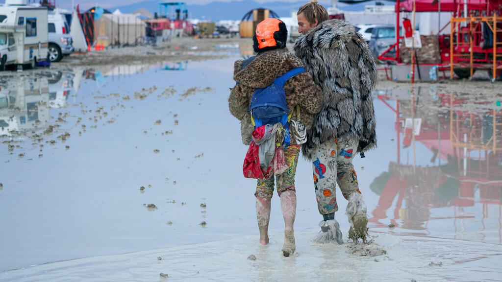 Walking in the mud at Burning Man in Nevada following torrential rains (Photo: Reuters/Trevor Hughes/USA TODAY NETWORKR) פסטיבל ברנינג מן בוץ בעקבות גשם רב ב נבאדה ארה"ב