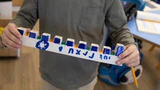 לוחמי צה"ל מדליקים נרות בתוך שטח רצועות עזה, עם חנוכיות שקושטו על ידי חברי הקהילות המפונות