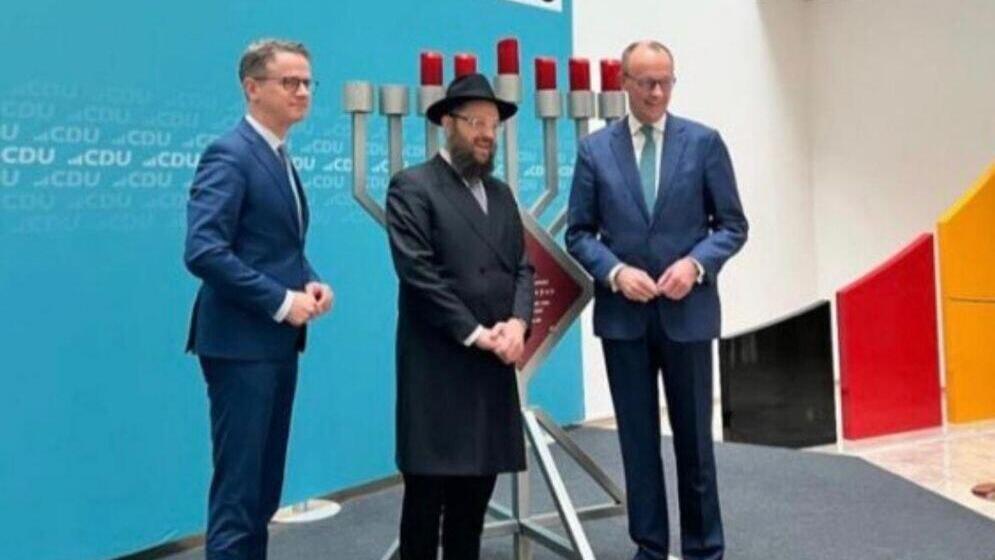 הקנצלר החדש לצד החנוכייה המוצבת מידי שנה במטה מפלגתו