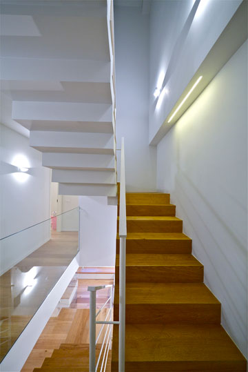 מדרגות עץ, מעקה ברזל לבן וקיר זכוכית (צילום: איתי סיקולסקי)