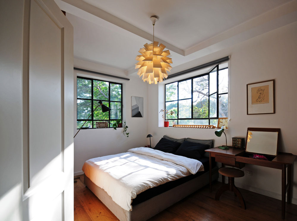 חדר השינה של ההורים. עבודות אמנות על הקירות, שולחן כתיבה דני משנות ה-40, ומנורת ה''ארטישוק'' מעל (צילום: נעמה כנפו)