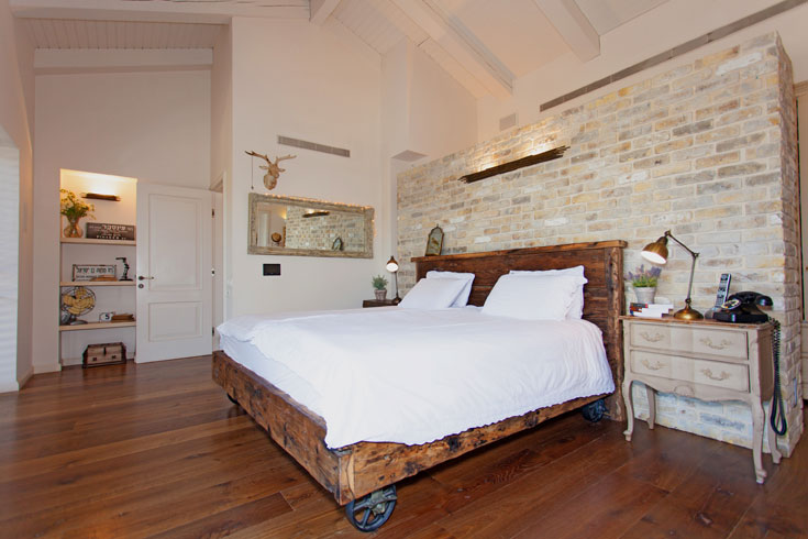 חדר השינה של הזוג. מיטה גדולה מעץ גושני וגלגלי פלדה ישנים (צילום: אבישי פינקלשטיין)