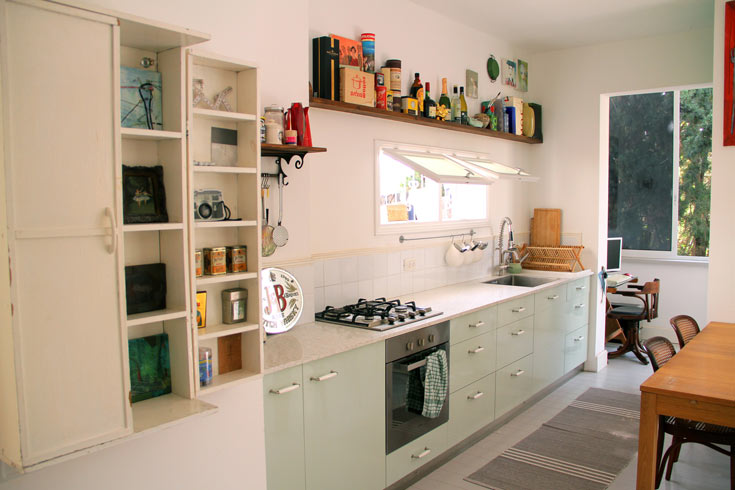 המטבח מורכב מארונות תכלכלים-ירקרקים, מדף עץ עליון ועבודות אמנות של פקט (צילום: ערן ג'גו)