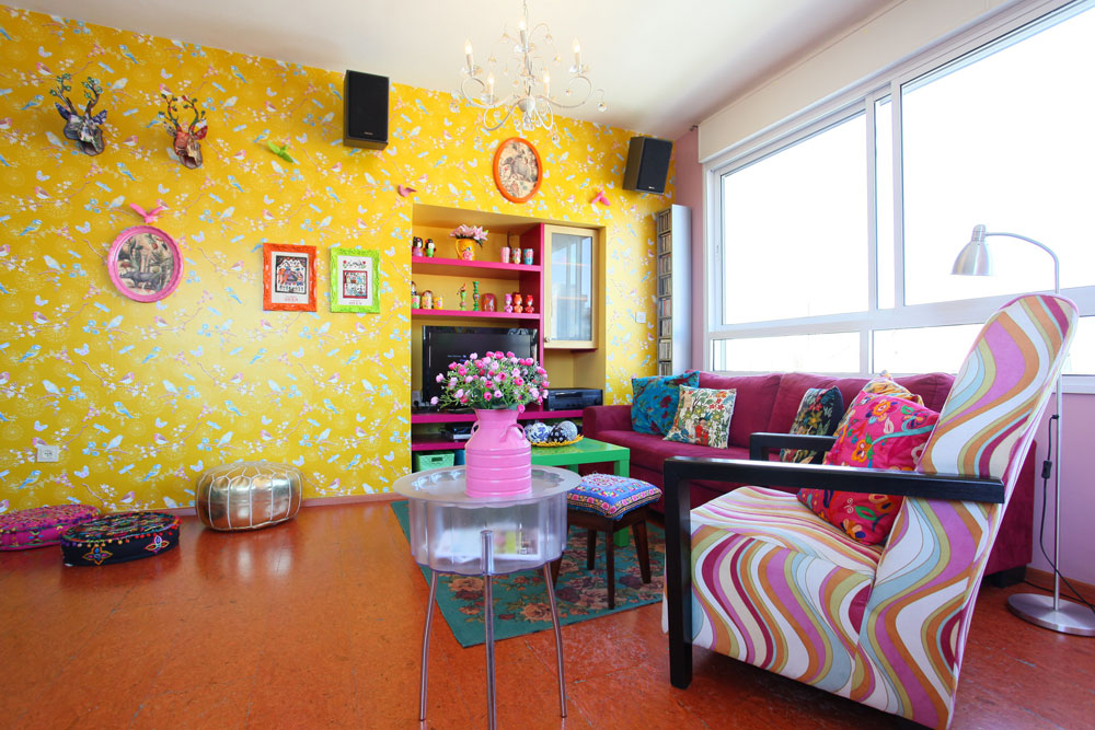 הסלון שמח ועמוס עם טפט צהוב, כריות רקומות, שטיח פרחוני, אוסף בבושקות וציפורים תלת-ממדיות שתלויות על הקיר (צילום: אבישי פינקלשטיין)