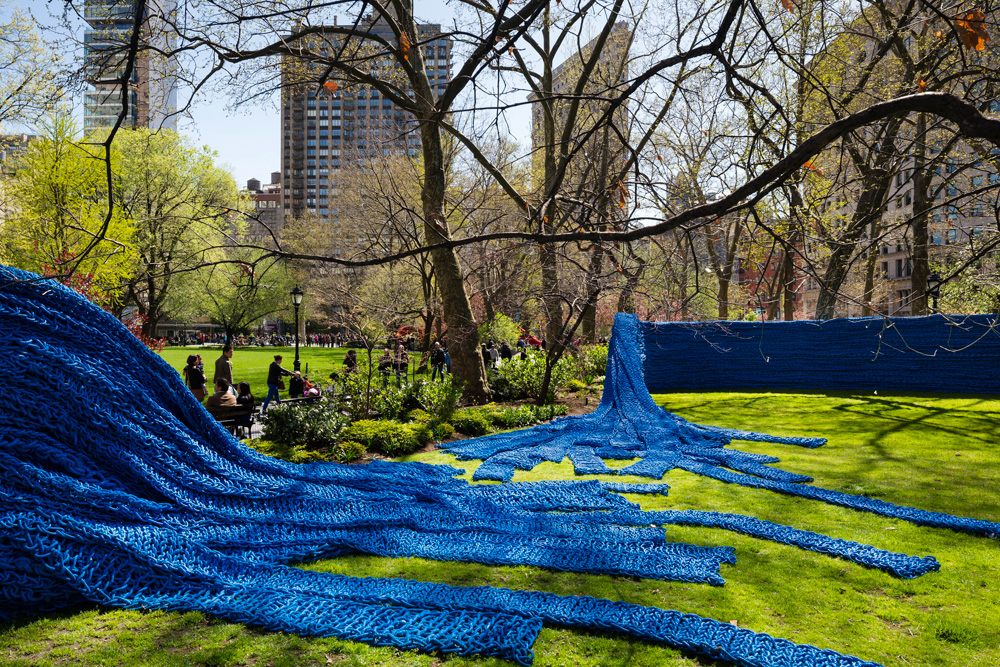 השטיח הכחול ב''מדיסון סקוור פארק''. עבודתה של אורלי גנגר, אישה צעירה וקטנת ממדים, מתאפיינת בקנה מידה גדול, בעבודה עם חבלים תעשייתיים ויותר מכל - במאמץ פיזי וסיזיפי. השטיחים תופסים צורה לאורך, לרוחב ולגובה, מכסים שטחים ונראים כמעט כמו יצורים חיים, מתפשטים (צילום: James Ewing / Courtesy of Madison Square Park Conservancy)