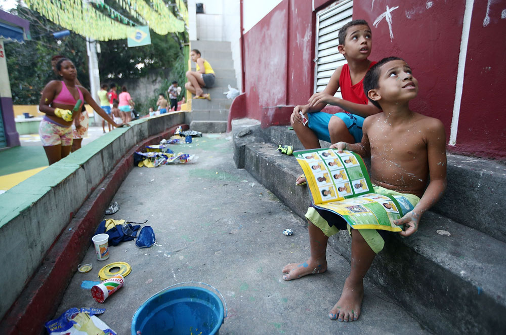יראו את המונדיאל מהצד הלא נכון שלו. ילד ברזילאי בפאבלות של ריו חוגג עם אלבום מדבקות של המונדיאל המתקרב שמצא ברחוב (צילום: gettyimages)
