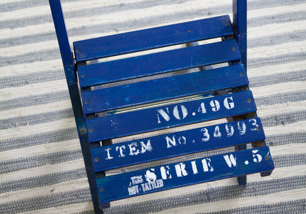 כיסא עץ  פשוט צבוע בכחול. על גבי המושב הוטבעו חותמות לבנות  (צילום: יוסי סליס)