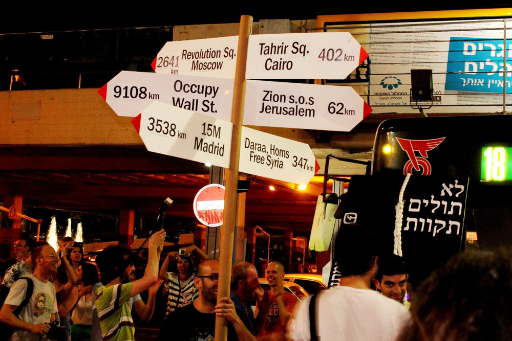 שלט ענקי שהכינו חברי הקבוצה, שממקם את המחאה הישראלית בהקשר העולמי שלה: מוול סטריט ועד דרעא ודמשק (צילום: עידן אלמוג)