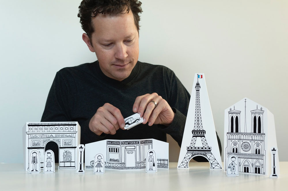 ג'ואל הנריקס ודגם מנייר של העיר  פריז. "הילדים יכולים לעשות כמעט את כל העבודה בעצמם: לצבוע, לחתוך ולקפל ואז לשחק איתם"  (מתוך madebyjoel.com)