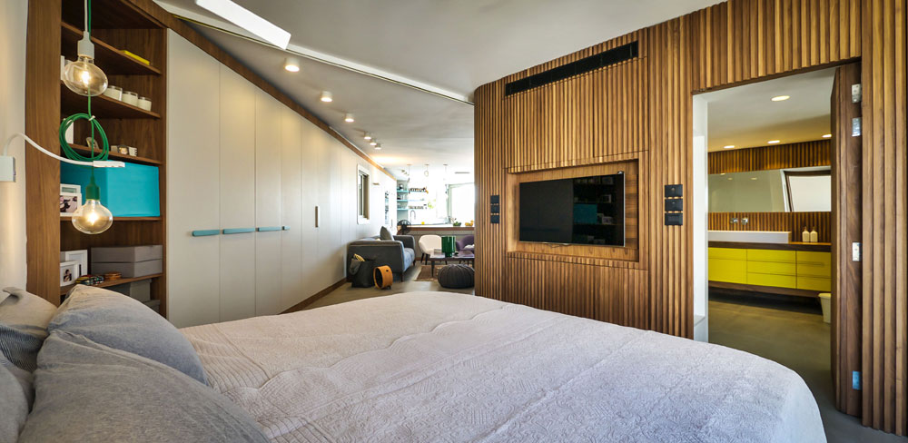 קיר סרגלי העץ שעליו מורכבת המחיצה מתעגל ונמשך לתוך חדר השינה (צילום: איתי סיקולסקי)