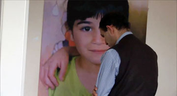 בסאם עראמין על רקע תמונת בתו (צילום מסך: יוטיוב)