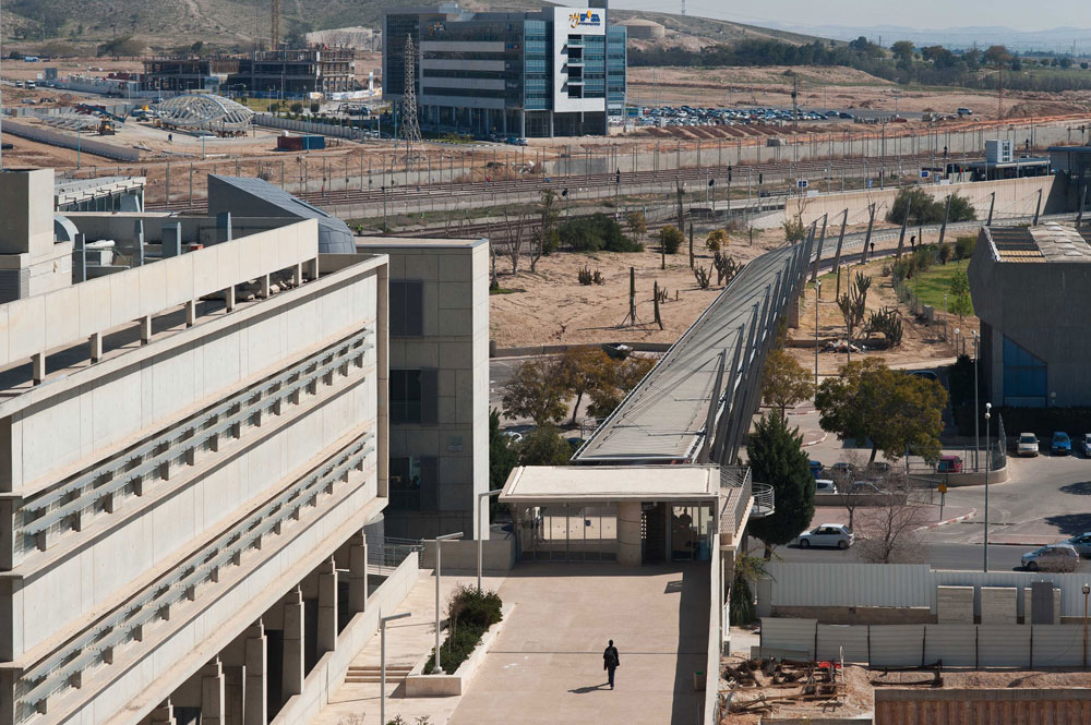 מצב קיים: הקמפוס מחובר בגשר לתחנת הרכבת האוניברסיטאית, והסטודנטים עוזבים בכל יום חמישי בצהריים בלי להיכנס לעיר. מאחור: פארק ההייטק הנבנה אוניברסיטת בן גוריון באר שבע
