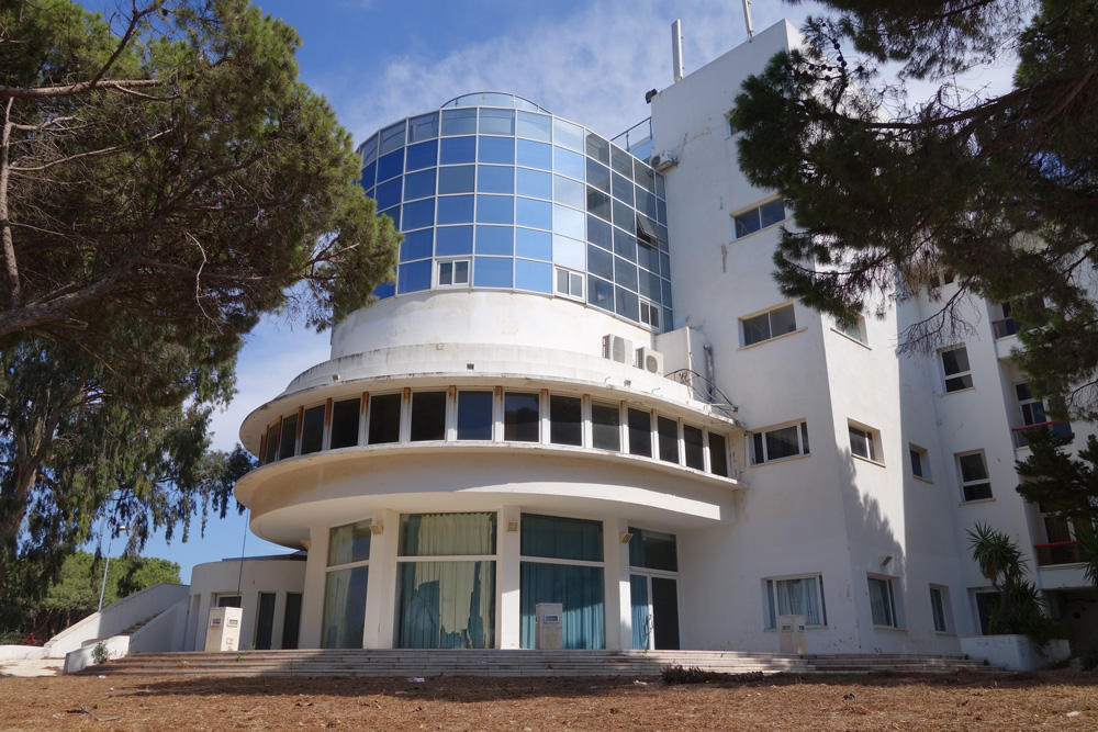 מלון הר הכרמל (במקור: טלטש). קומת העמודים הייתה פתוחה במקור, אך במהלך השנים היא נסגרה והפכה לאולם אירועים. חדר האוכל נמצא מעליה. הקומה הכחולה נוספה ב-1998 מקומות נטושים מלון הר כרמל