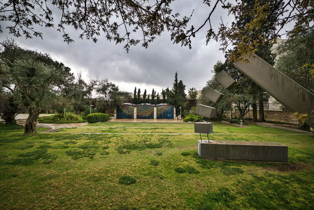 פסל של מנשה קדישמן בגן המקיף את הבניין. ברקע: קיר הזכוכית של בית הכנסת שעיצבה מירה מיילור בית הנשיא