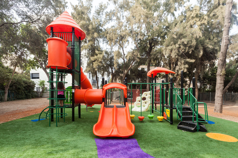 גן משחקים בבית הספר ''אלומות'' ברמת אביב. נדמה שאסור להשאיר את האדמה חשופה - היא מוכרחה להיות ירוקה, גם אם הירוק הזה הוא פלסטיק דשא סינתטי גן שעשועים בית ספר אלומות